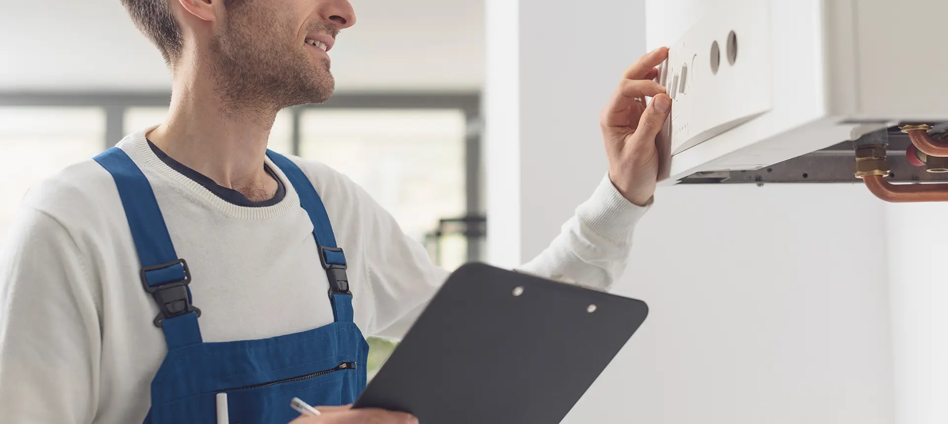 Mann in Arbeitskleidung stellt Gasboiler ein