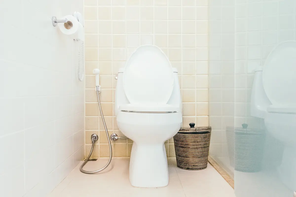 Eine weiße Toilette neben einem Korb