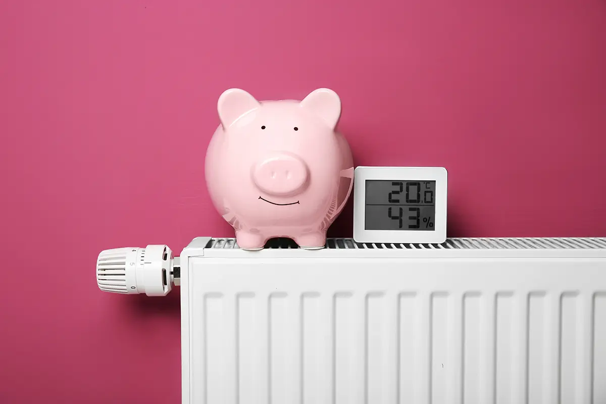 pur - Kosteneinsparung Sparschwein und Thermometer auf einem Heizkörper