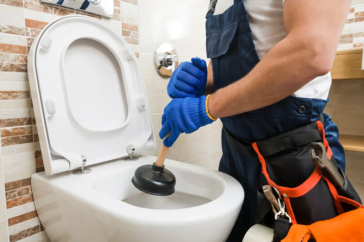 Mann beseitigt Verstopfung in Toilette