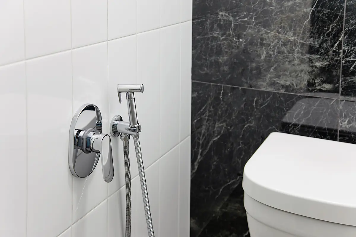 pur - WC-Armaturen und Spezialanwendungen Weiße Toilette in Badezimmer mit Wand aus schwarz-weißen Fliesen