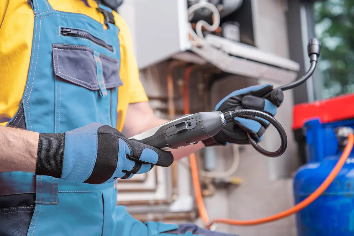 Ein Mann in Latzhose hält ein Gaslecksuchgerät in der Hand