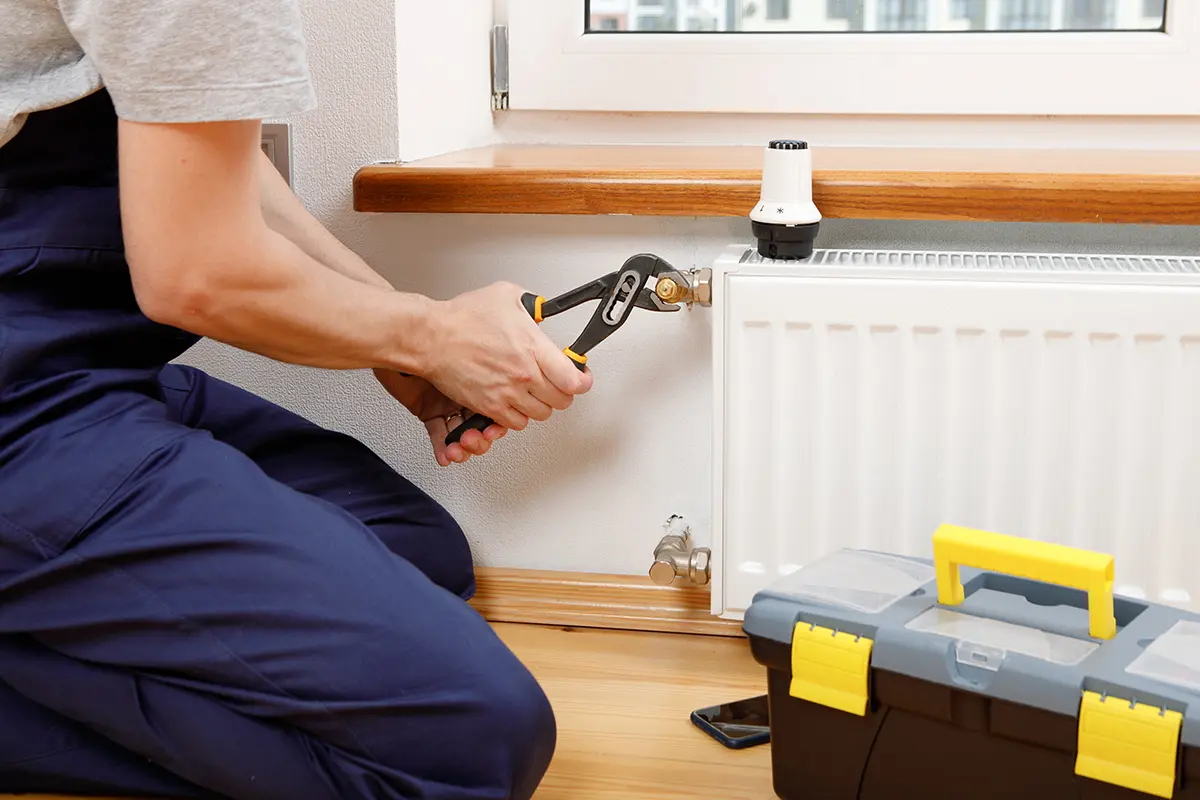 pur gmbh - Notdienst - Mann repariert Heizkörper mit Schraubenschlüssel