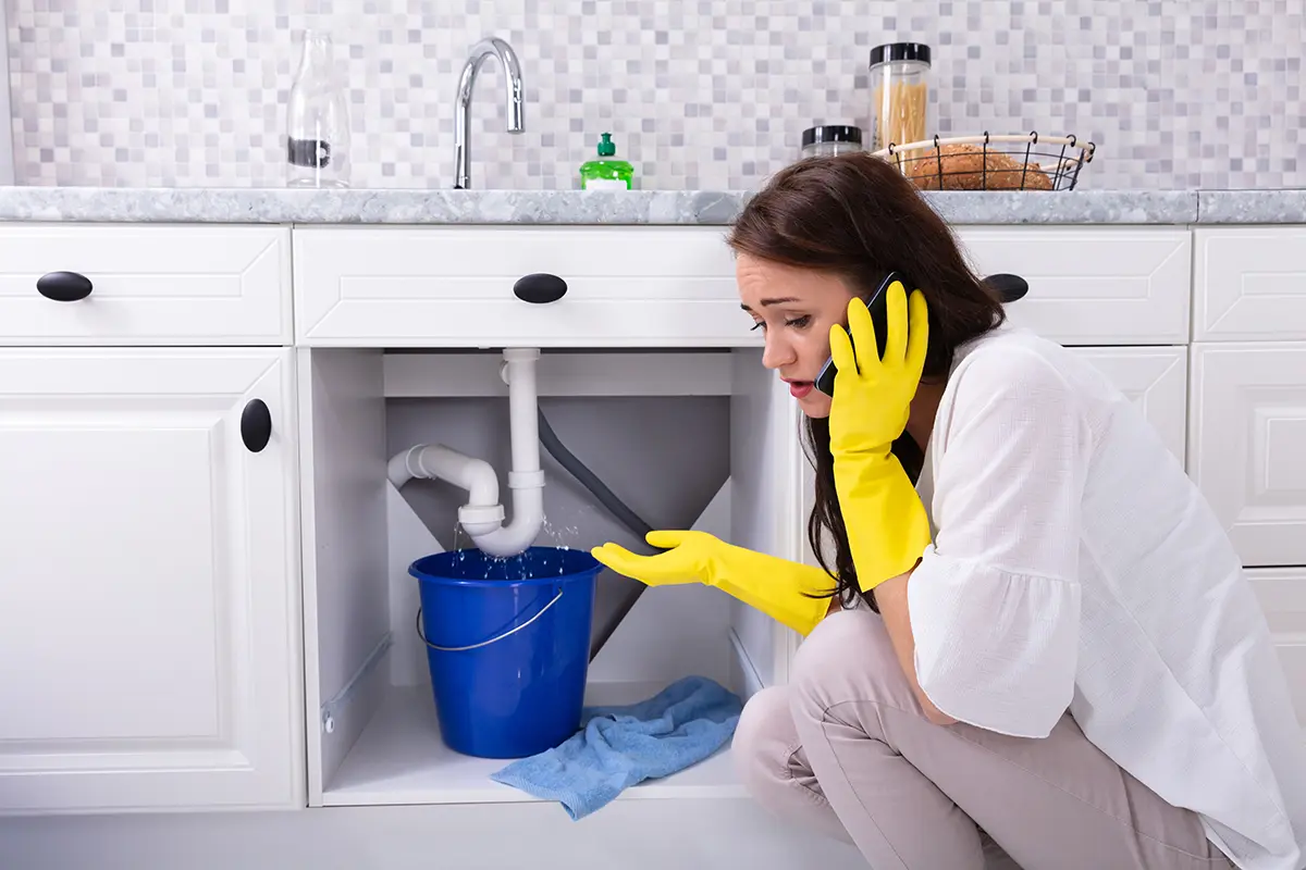 Frau ruft Techniker wegen undichtem Waschbecken in Küche an